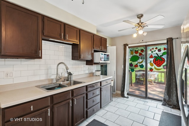 kitchen with light tile patterned flooring, sink, dark brown cabinets, decorative backsplash, and ceiling fan