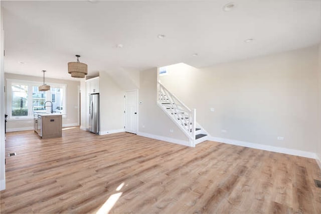 unfurnished living room featuring light hardwood / wood-style flooring and sink