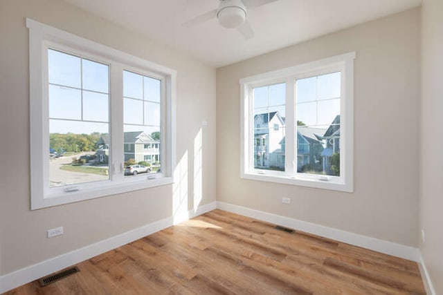 spare room with ceiling fan, a healthy amount of sunlight, and wood-type flooring