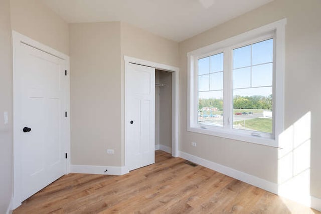 unfurnished bedroom with light wood-type flooring and a closet