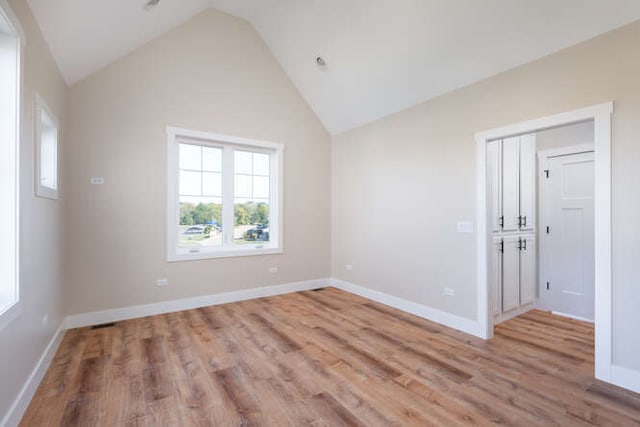 unfurnished room with light wood-type flooring and high vaulted ceiling