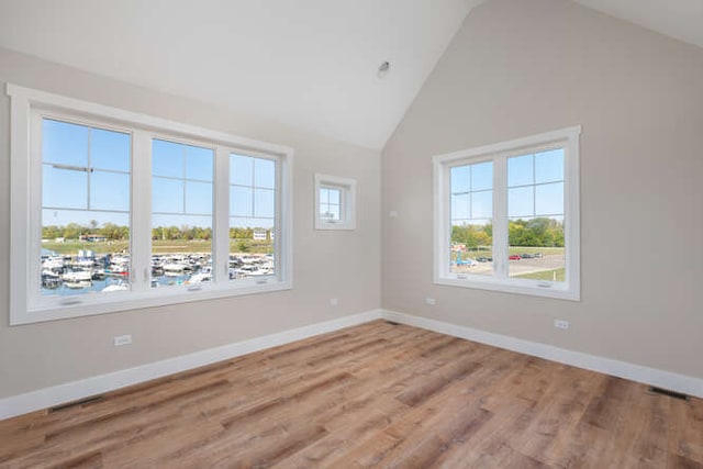 spare room featuring hardwood / wood-style flooring and high vaulted ceiling