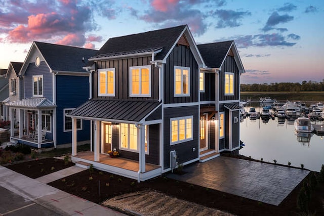 back house at dusk featuring a porch and a water view