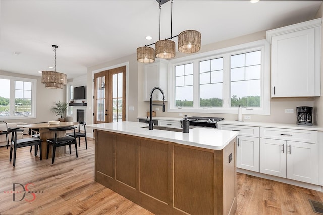 208 Leeward Way, Ottawa, IL 61350 - kitchen featuring light wood-style floors, an island with sink, light countertops, decorative light fixtures, and white cabinets
