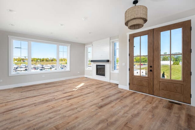 unfurnished living room with hardwood / wood-style floors, french doors, and a healthy amount of sunlight