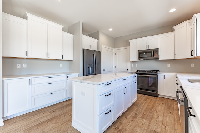 kitchen with white cabinets, light wood-type flooring, and black appliances