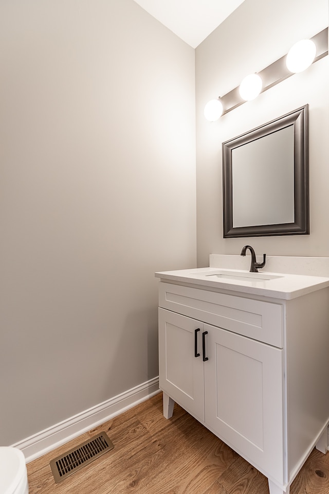 bathroom featuring toilet, vanity, and hardwood / wood-style floors