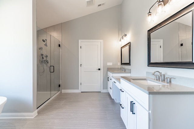 bathroom with vaulted ceiling, a shower with door, and vanity