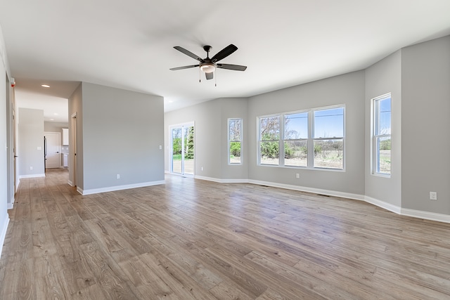 empty room with light hardwood / wood-style floors, ceiling fan, and a healthy amount of sunlight