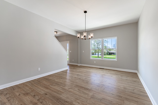 unfurnished room with light hardwood / wood-style flooring and a notable chandelier