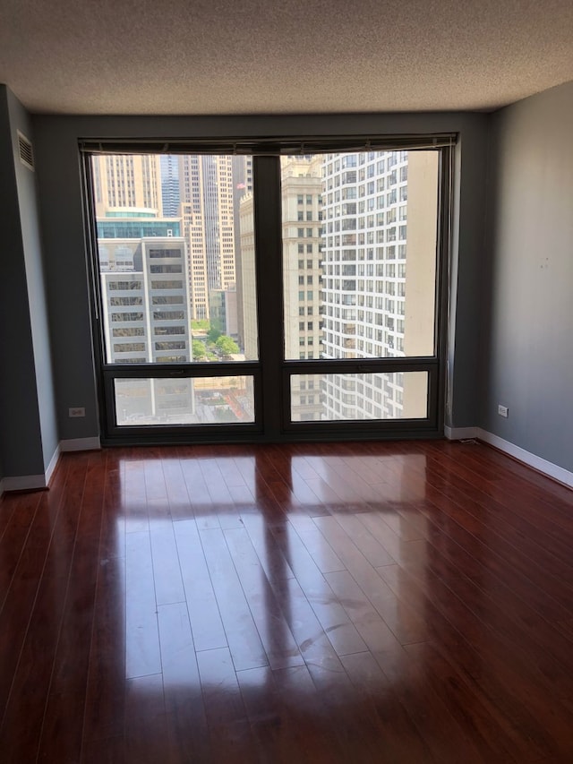 unfurnished room with a textured ceiling and dark hardwood / wood-style flooring