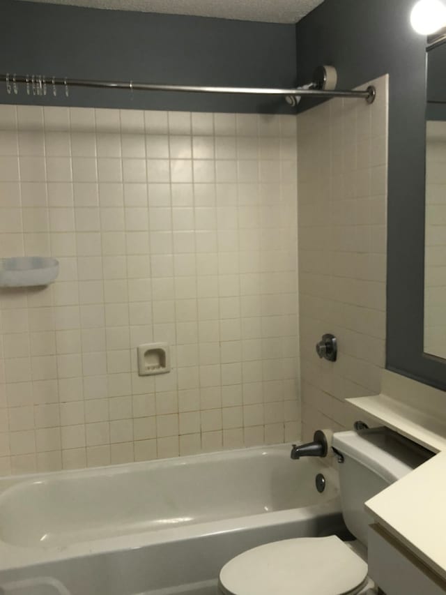 full bathroom featuring tiled shower / bath, vanity, toilet, and a textured ceiling