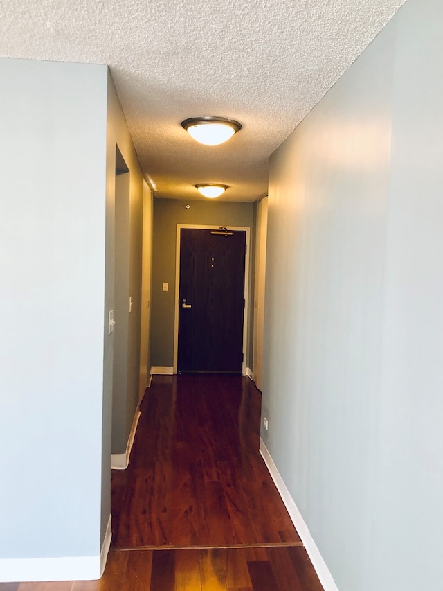 hallway featuring wood-type flooring and a textured ceiling