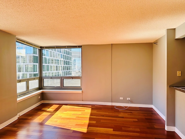 spare room featuring dark hardwood / wood-style flooring and a textured ceiling