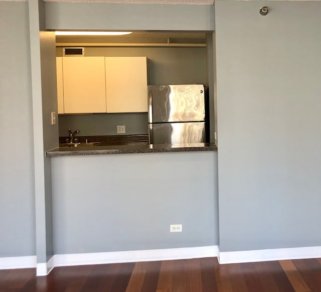 kitchen featuring sink, dark stone countertops, stainless steel fridge, and dark hardwood / wood-style floors