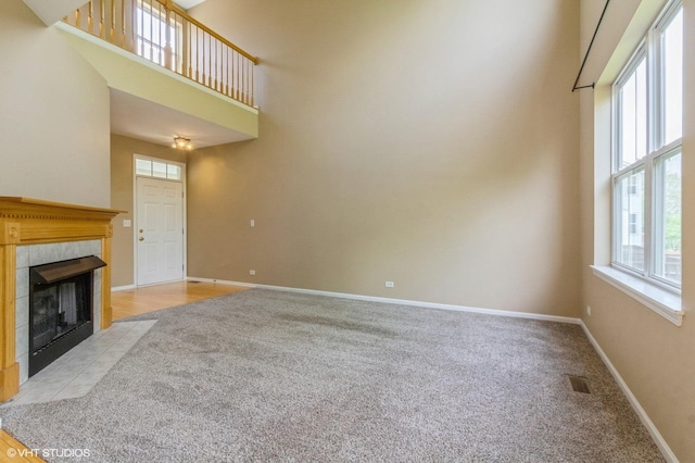 211 Grand Ridge Rd, Saint Charles, IL 60175 - unfurnished living room with a towering ceiling, light carpet, baseboards, and a tiled fireplace