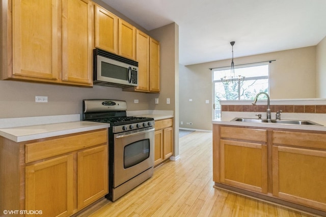 211 Grand Ridge Rd, Saint Charles, IL 60175 - kitchen with stainless steel appliances, a sink, light wood-style flooring, a chandelier, and light countertops
