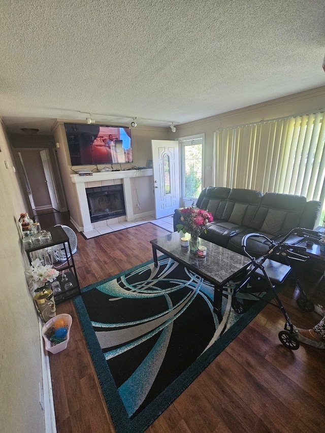 living room featuring a tile fireplace, a textured ceiling, and wood-type flooring