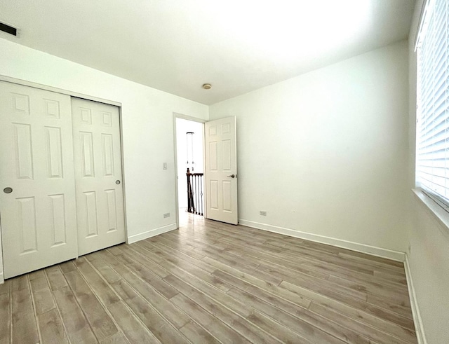 unfurnished bedroom with a closet and light wood-type flooring