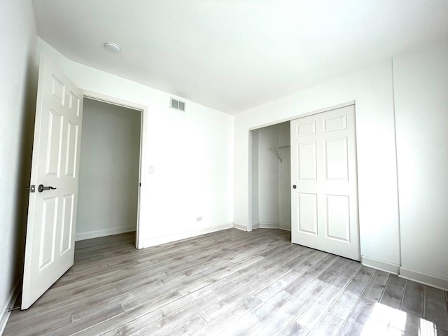 unfurnished bedroom with light hardwood / wood-style floors and a closet