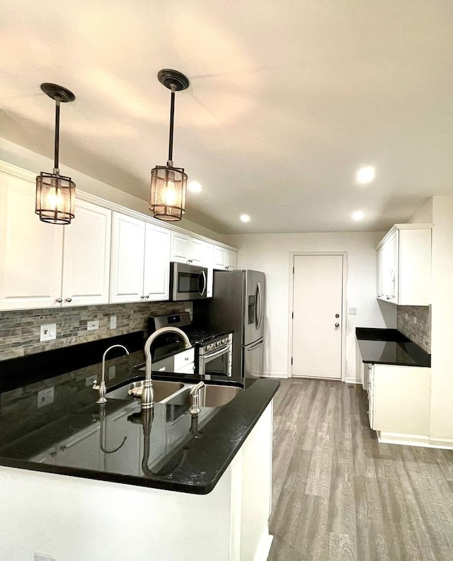 kitchen featuring decorative backsplash, white cabinetry, stainless steel appliances, and decorative light fixtures