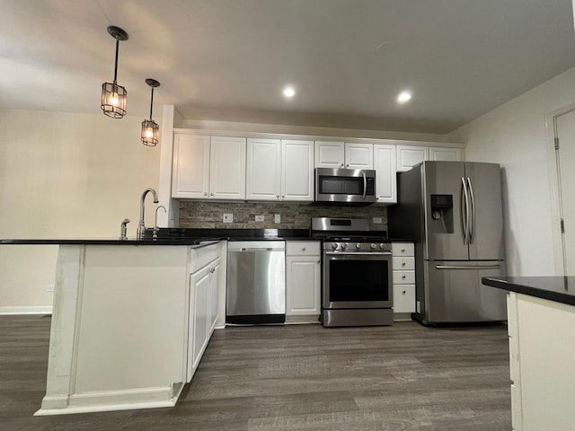 kitchen with white cabinets, hanging light fixtures, dark hardwood / wood-style floors, decorative backsplash, and appliances with stainless steel finishes