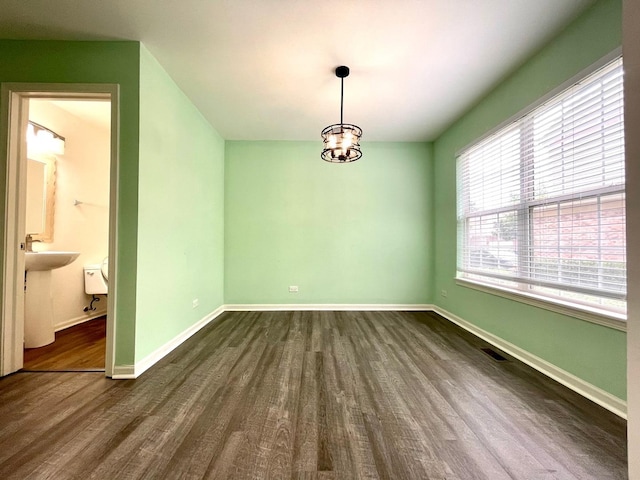 unfurnished dining area featuring sink, dark wood-type flooring, and a notable chandelier