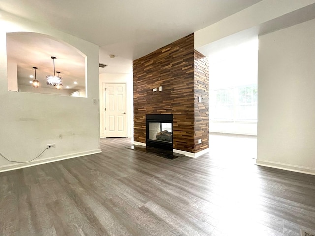 unfurnished living room with a multi sided fireplace and dark wood-type flooring