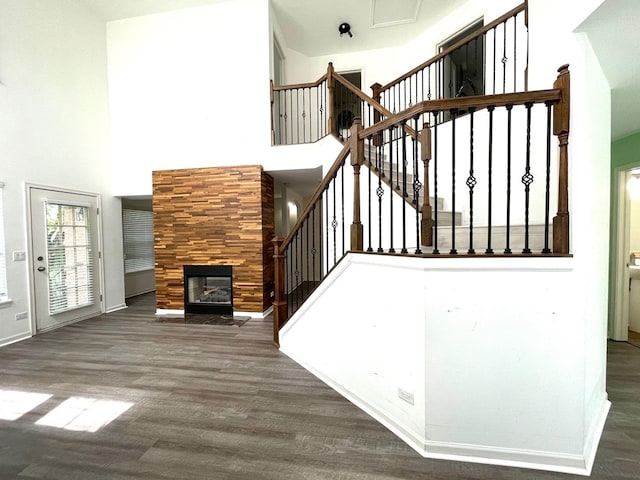 staircase with hardwood / wood-style floors, a towering ceiling, and a tiled fireplace