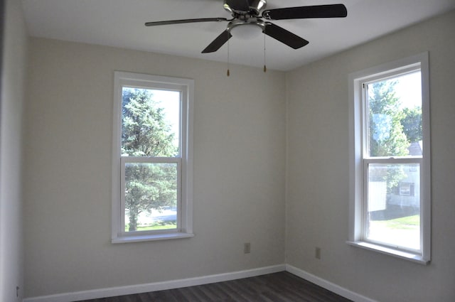 spare room featuring a wealth of natural light, ceiling fan, and dark hardwood / wood-style floors