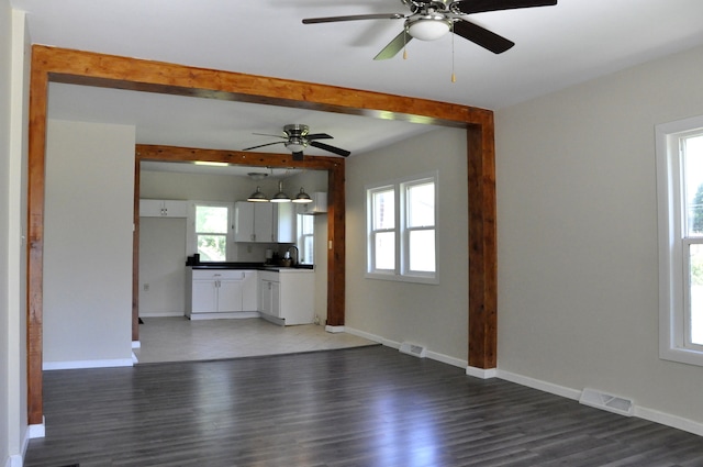 unfurnished living room with ceiling fan, sink, and dark wood-type flooring