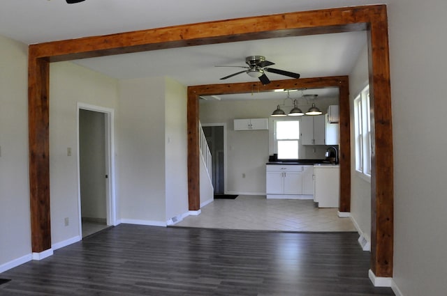 unfurnished living room featuring ceiling fan, dark hardwood / wood-style flooring, and sink