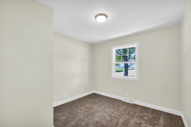 spare room with visible vents, baseboards, and dark colored carpet