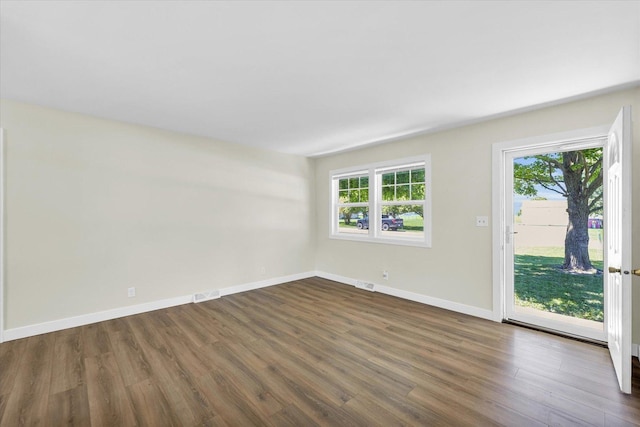 empty room with a healthy amount of sunlight and dark hardwood / wood-style flooring