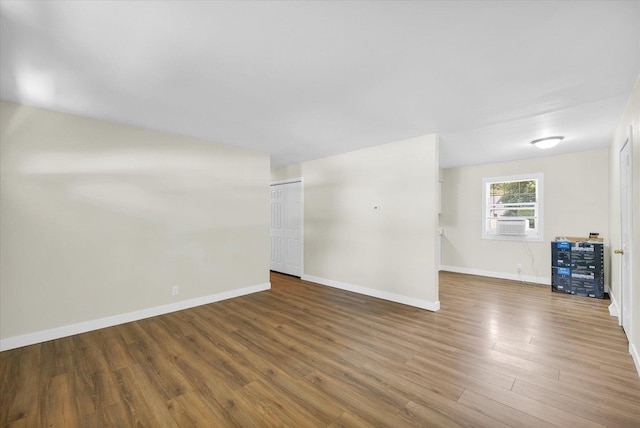 unfurnished room with cooling unit, baseboards, and wood finished floors