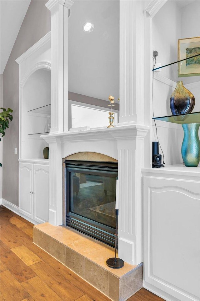 room details with ornate columns, baseboards, wood finished floors, and a tile fireplace