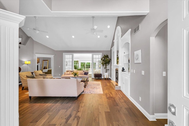 living room featuring built in features, visible vents, ceiling fan, and hardwood / wood-style flooring