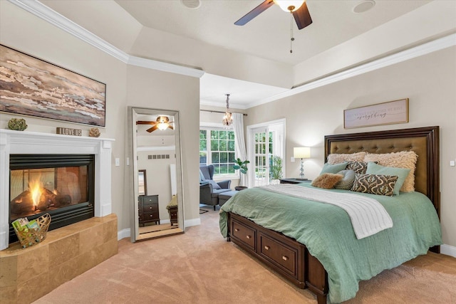 bedroom featuring a tray ceiling, a fireplace, light colored carpet, ornamental molding, and baseboards