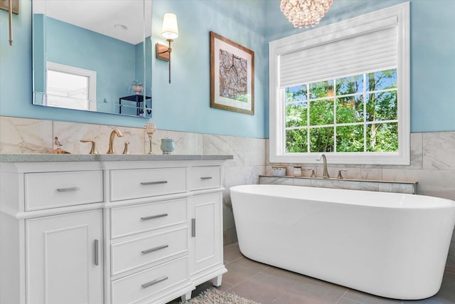 bathroom featuring tile patterned flooring, a freestanding bath, tile walls, and vanity