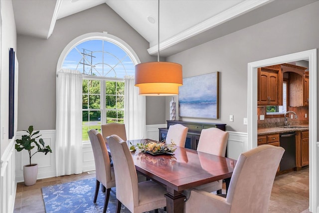 dining area with a wainscoted wall, vaulted ceiling, a decorative wall, and light tile patterned flooring