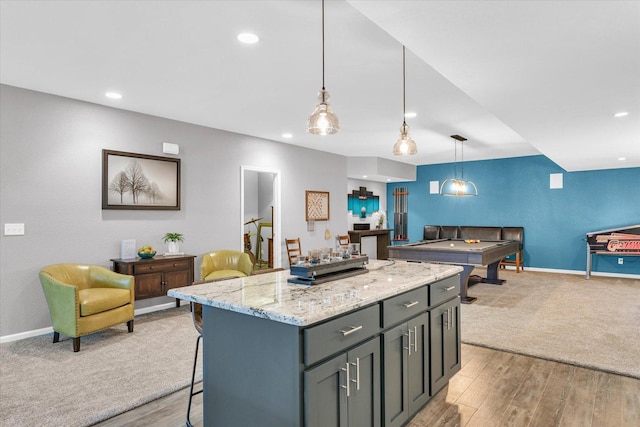 kitchen with a center island, a kitchen breakfast bar, open floor plan, light stone countertops, and decorative light fixtures