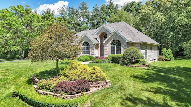 view of front of property with roof with shingles, a front lawn, and brick siding