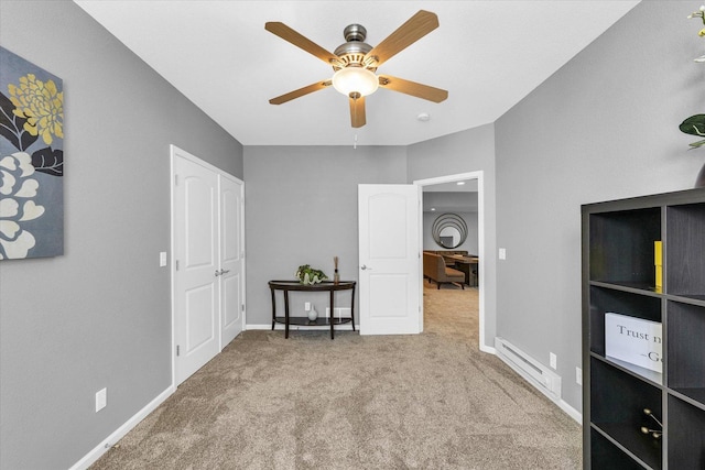 unfurnished bedroom featuring carpet floors, a baseboard heating unit, baseboards, and a ceiling fan