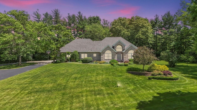 view of front of property featuring stone siding and a lawn