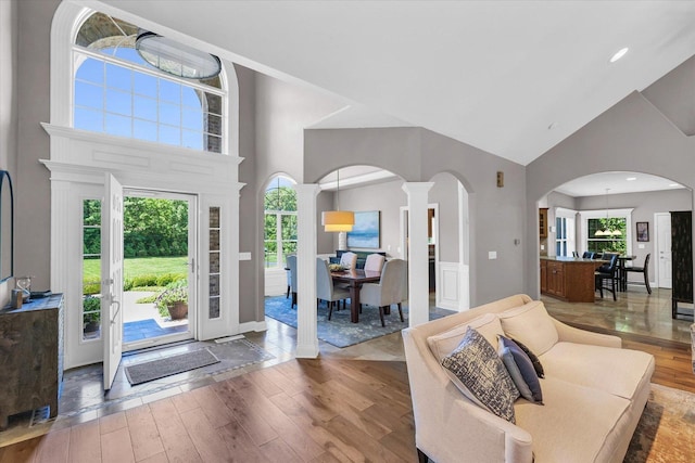 entryway featuring high vaulted ceiling, arched walkways, plenty of natural light, and hardwood / wood-style floors