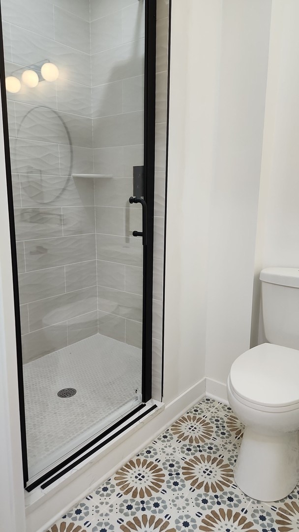 bathroom featuring an enclosed shower, tile flooring, and toilet