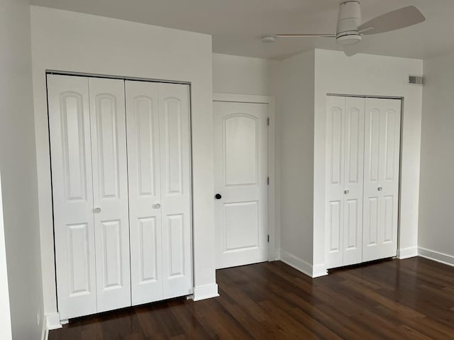 unfurnished bedroom featuring dark hardwood / wood-style flooring and two closets