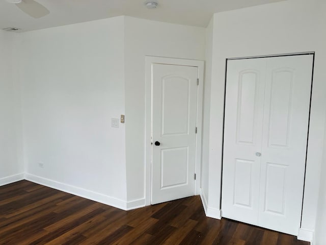 unfurnished bedroom with a closet, ceiling fan, and dark hardwood / wood-style flooring