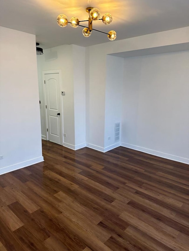 empty room with a chandelier and dark hardwood / wood-style flooring