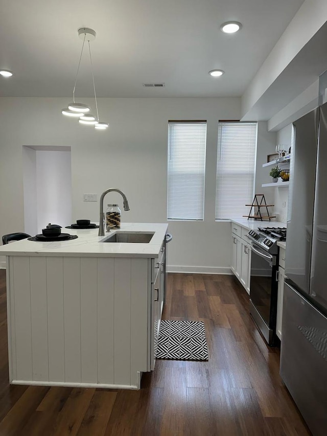 kitchen with hanging light fixtures, dark wood-type flooring, a center island with sink, stainless steel appliances, and sink